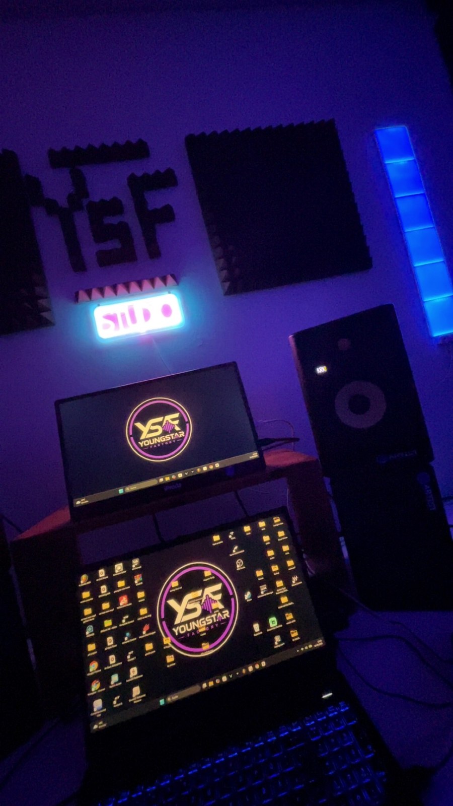 Zwei Bildschirme mit Youngstar-Factory-Logo am Arbeitsplatz im violetten Studio-Licht