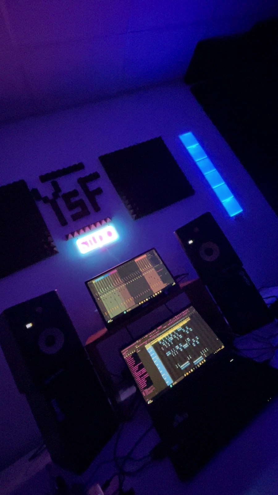 Bildschirme mit Musiksoftware zwischen zwei Monitorboxen im blau-violetten Licht