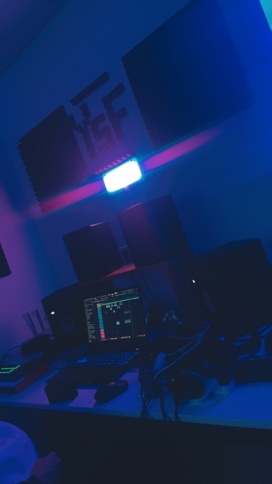 Blau beleuchteter Arbeitsplatz mit Monitorboxen und Musiksoftware auf einem Bildschirm